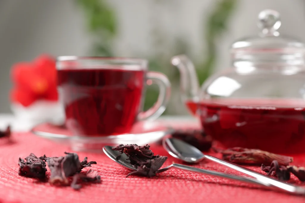 chaleira e xícara em cima da mesa com chá de hibisco